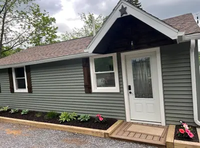 a house with a white door and some flowers at Adirondack Home #8 in Hamilton