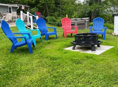 a group of colorful chairs sitting around a fire pit at Adirondack Home #8 in Hamilton