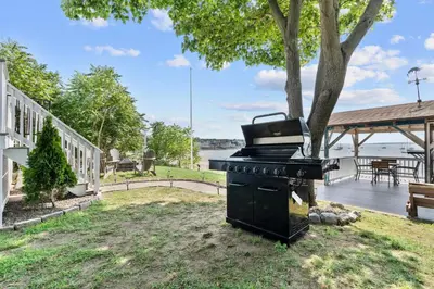 a grill sitting in the grass next to a tree at Beachfront Apartment - 8 min from downtown in New Haven
