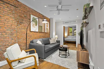 a living room with a couch and a brick wall at Stylish Escape in the East Village in New York