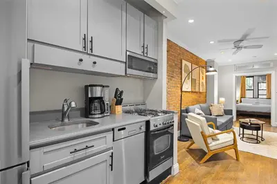 a kitchen with a stove top oven next to a living room at Stylish Escape in the East Village in New York