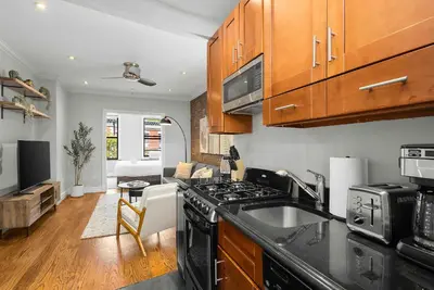 a kitchen with a stove top oven next to a living room at Chic NYC Escape in Vibrant Downtown in New York