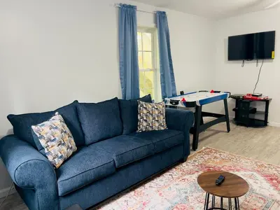 a living room with a blue couch and a table at Explore Poconos with Fire pit, Games, Grill in Tobyhanna