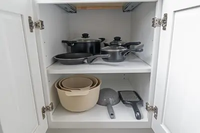 a cupboard with pots and pans in it at Style & Comfort 3 Rooms -15 min from NYC in West New York