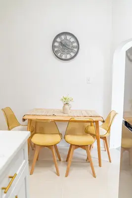 a dining room table and chairs with a clock on the wall at Moderno y Céntrico Estacionamiento Privado A 15 min de NYC in Jersey City