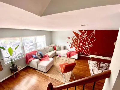 a person sitting on a couch in a living room at Easy PATH&Bus access- NYC designer home & Terrace in Jersey City