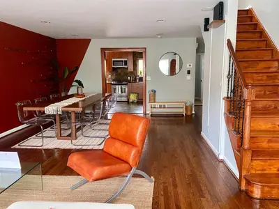 a living room with an orange chair and a table at Easy PATH&Bus access- NYC designer home & Terrace in Jersey City