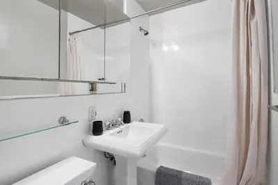 a white bathroom with a sink and a mirror at Trendy East Village Escape in New York