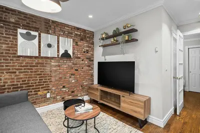 a living room with a brick wall and a flat screen tv at Trendy East Village Escape in New York