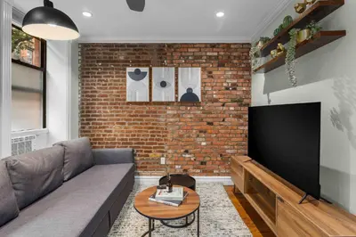 a living room with a couch and a flat screen tv at Trendy East Village Escape in New York
