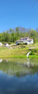 a large pond with a house in the background at Susquehanna Waterfall Haven in Susquehanna