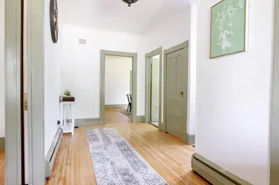 a hallway with white walls and a rug on a hard wood floor at Expansive Victorian close to Saratoga Springs and Lake George in Corinth