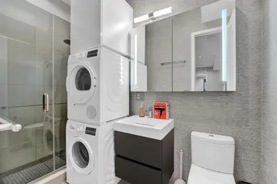 a bathroom with a washer and dryer next to a toilet at Modern West Village 1BR Garden steps to subway in New York