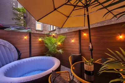 a patio with a hot tub and an umbrella at Modern West Village 1BR Garden steps to subway in New York