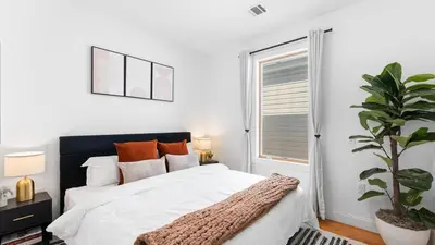 a bedroom with a bed with white sheets and a plant at Luxury Retreat Walk 2 PATH NYC in Mins Parking in Jersey City