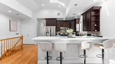 a kitchen with a large white island with stools at Luxury Retreat Walk 2 PATH NYC in Mins Parking in Jersey City