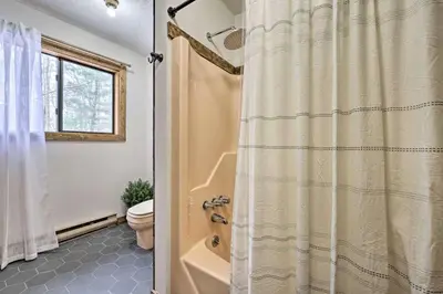 a bathroom with a shower curtain and a toilet at Luxurious Cabin by Lakes & Ski in Lake Ariel