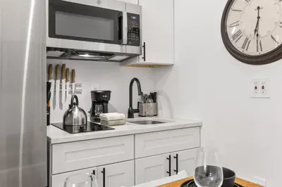 a white kitchen with a microwave and a sink at 2BR and 2BA in Historic Brownstone near Subway in New York