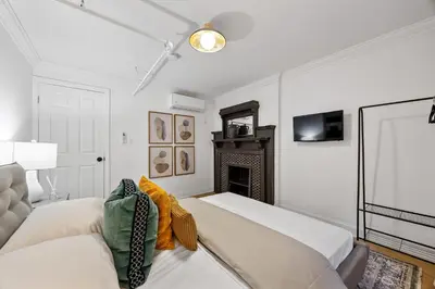 a white room with a bed and a fireplace at Brownstone 2 Bed with Private Backyard near Subway in New York