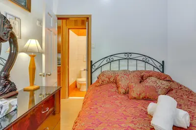 a bedroom with a bed with a red comforter at 5 Mi to Swinging Bridge Reservoir Cabin with Porch! in Mongaup Valley