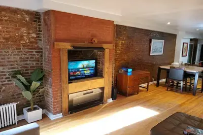 a living room with a tv in a brick wall at Garden Apartment in New York