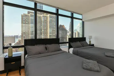 a bedroom with two beds and a large window at Opulent 2BR Duplex - Iconic Midtown Views in New York