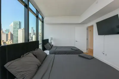 a bedroom with two beds and a flat screen tv at Opulent 2BR Duplex - Iconic Midtown Views in New York
