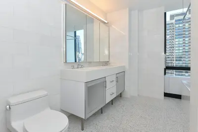 a white bathroom with a toilet and a sink at Opulent 2BR Duplex - Iconic Midtown Views in New York