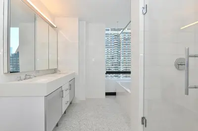 a white bathroom with two sinks and a shower at Opulent 2BR Duplex - Iconic Midtown Views in New York