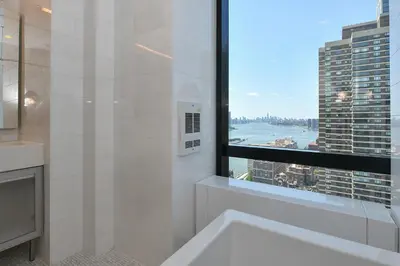 a bathroom with a large window and a bath tub at Opulent 2BR Duplex - Iconic Midtown Views in New York