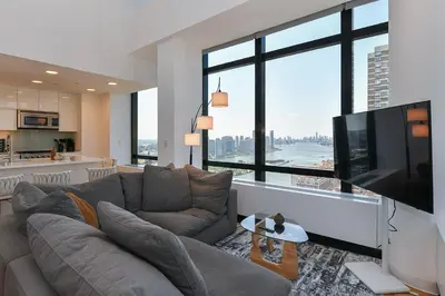 a living room with a couch and a flat screen tv at Opulent 2BR Duplex - Iconic Midtown Views in New York