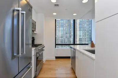 a kitchen with stainless steel appliances and a large window at Opulent 2BR Duplex - Iconic Midtown Views in New York