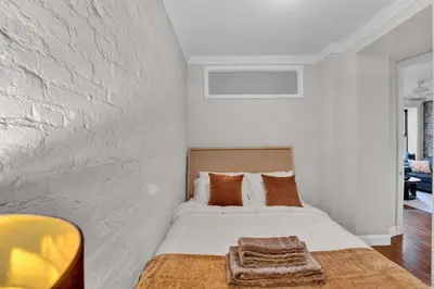 a white bedroom with a bed with a blanket at Stylish 3BR-2BA in Gramercy -Modern & Central in New York