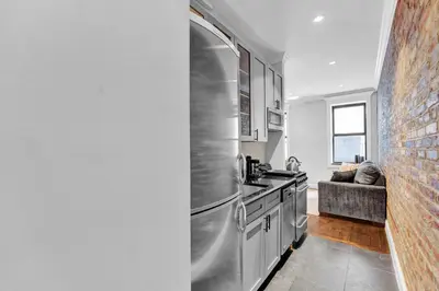 a kitchen with a stainless steel refrigerator next to a couch at Stylish 3BR-2BA in Gramercy -Modern & Central in New York