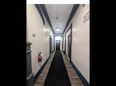 a long hallway with white walls and a black carpet at Sava apt rentals in Newark