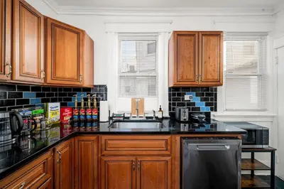 a kitchen with wooden cabinets and a sink at Whole House Near NYC and Transit with Game Room Fire Pit and King Bed in New Rochelle