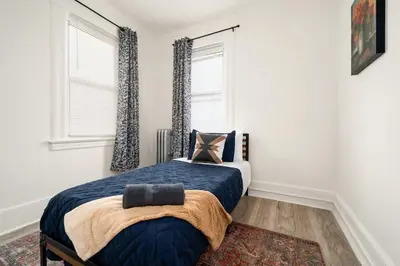 a bedroom with a bed and two windows at Whole House Near NYC and Transit with Game Room Fire Pit and King Bed in New Rochelle