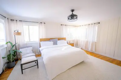 a white bedroom with a large bed and a chair at Oscawana Lake Escape in Putnam Valley