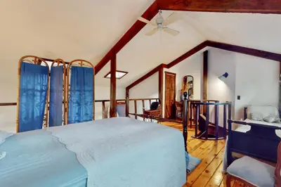 a bedroom with a large bed with blue curtains at Adirondacks in Style! Lake House with Deck, Fire Pit in Hadley