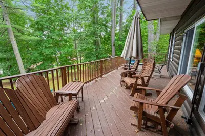 a deck with chairs and an umbrella and an umbrella at Adirondacks in Style! Lake House with Deck, Fire Pit in Hadley