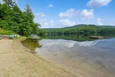 a view of a lake with a boat on the shore at Adirondacks in Style! Lake House with Deck, Fire Pit in Hadley
