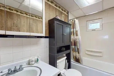 a bathroom with a sink and a black cabinet at Adirondacks in Style! Lake House with Deck, Fire Pit in Hadley