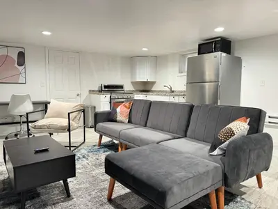 a living room with a couch and a kitchen at Open Serene Suite - 10mins-EWR, 25mins-NYC in Irvington