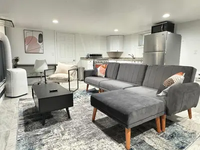 a living room with a couch and a kitchen at Open Serene Suite - 10mins-EWR, 25mins-NYC in Irvington