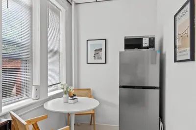 a kitchen with a refrigerator and a small table at Modern Studio - Parking Available - 15 min NYC in Jersey City