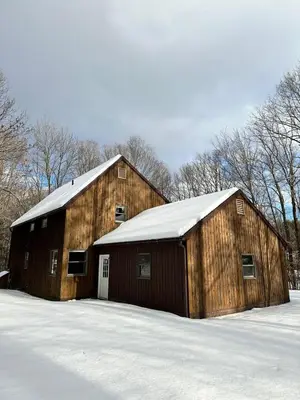 a large wooden barn with a snow covered roof at Nature's Nest - Woodland Retreat - Fireplace - Quiet and Cozy in Bethlehem
