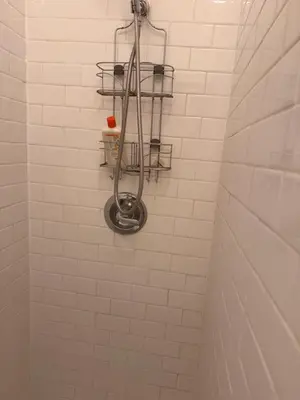 a white tiled bathroom with a shower with a shelf at Kitchenette in New York