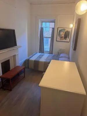 a small bedroom with a bed and a television at Kitchenette in New York