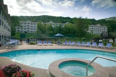 a large swimming pool with chairs and a building at 2 BR JIMINY PEAK w Mountain Views SLEEPS 7 Gorgeous in Hancock