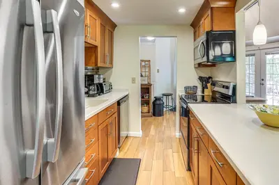 a kitchen with wooden cabinets and a stainless steel refrigerator at Ski, Snowshoe and Fish Dome Escape in Nature! in Warren